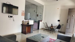 Ein Wohnzimmer mit Fernseher, Couchtisch und Essbereich mit Stühlen.