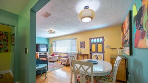 Una sala de estar acogedora con chimenea, un comedor con mesa y sillas blancas, y una cocina con armarios de madera.