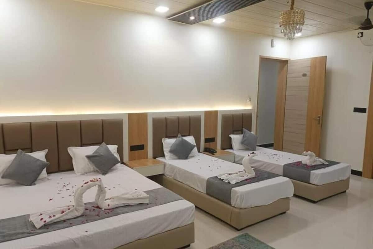 Une chambre d’hôtel avec trois lits, chacun doté d’une tête de lit, d’oreillers et d’une pile de serviettes.
