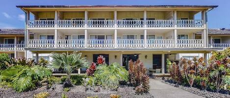 A two-story hotel with a balcony on each floor, a covered entrance, and tropical landscaping.