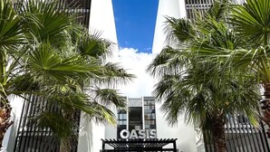 Un edificio moderno con ingresso recintato, palme e cielo azzurro intenso.