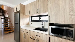 Una cocina moderna con armarios de madera, un refrigerador de acero inoxidable, un fregadero y un microondas integrado.