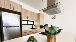 Una cocina moderna con armarios de madera, un refrigerador de acero inoxidable, un microondas y una estufa.