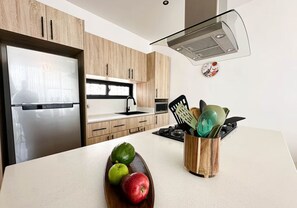 A modern kitchen with wooden cabinets, a stainless steel refrigerator, a microwave, and a stove. - Tropical Oasis in Bayahibe with Pool and Private Terrace with Jacuzzi and BBQ! (Bayahíbe)