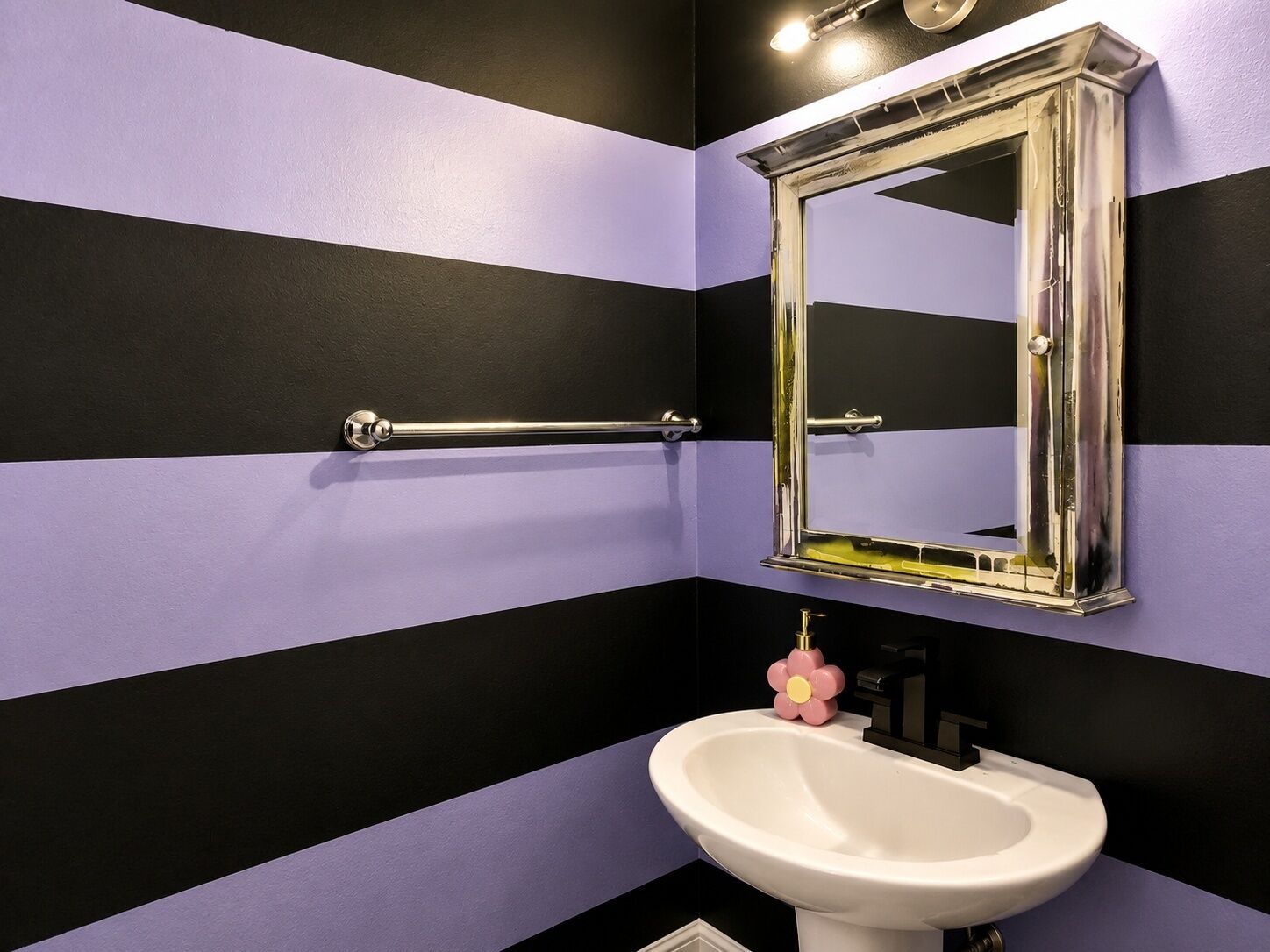 Een badkamer met een witte wastafel, een spiegel en een handgreep.