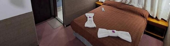 A hotel room with a bed, a nightstand, and a door. - Hotel Lincoln (Villa Gesell)