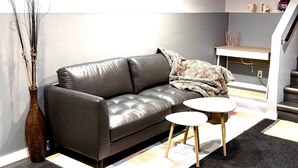 A modern living room with a leather sofa, a small round table, and a decorative vase. - Family-Friendly 2-Bedroom Unit with Full Bathroom, Living Room, TV & Kitchen (Winnipeg)