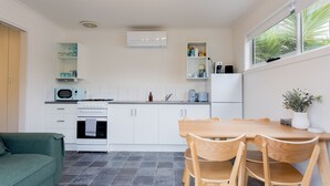 Una cocina moderna con armarios blancos, microondas, estufa y un comedor con sillas y mesa de madera.