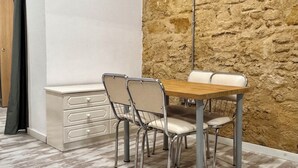 Un coin repas avec un mur en pierre, une table en bois et quatre chaises.