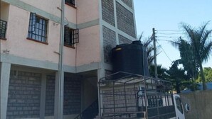 A multi-story building with a flat facade, large windows, and a visible water tank on the ground floor.