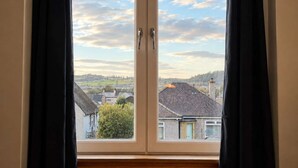 A room with a large window featuring a view of a town and a clear sky. - The Yellow Door, Inverness (Inverness)