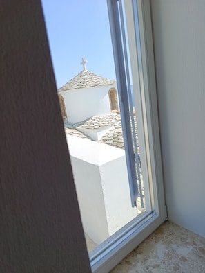 Une vue à travers la fenêtre d’un bâtiment surmonté d’une croix, ce qui laisse supposer qu’il s’agit d’un édifice religieux ou historique.