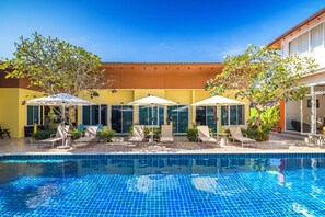 Una piscina al aire libre, sombrillas, sillones reclinables de piscina