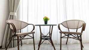 A room with two wicker chairs, a small glass table, and a potted plant. - Tongtong Garden Holiday Hotel (Rawai)