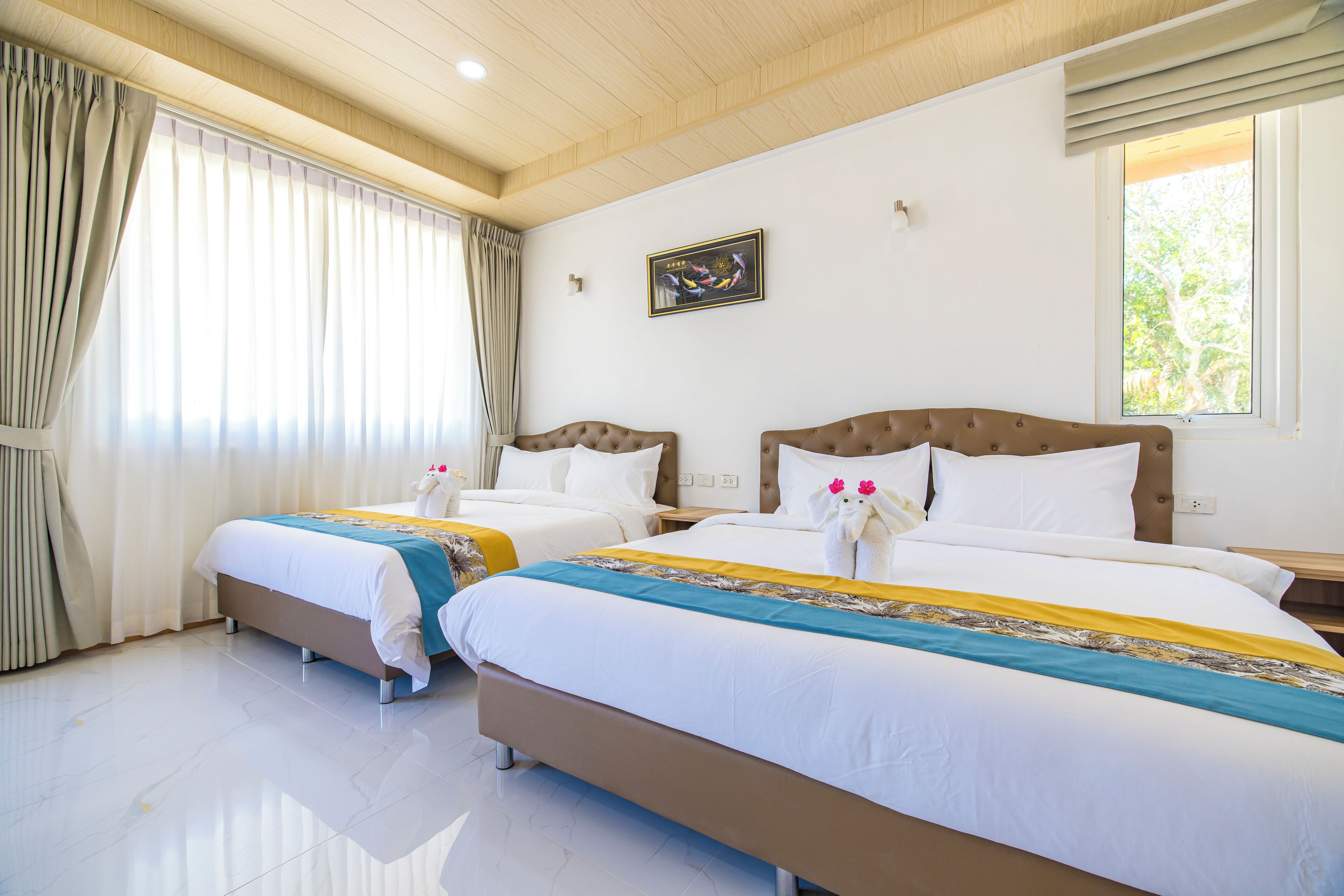Habitación de hotel con dos camas, un ventanal con cortinas, un cuadro en la pared y techo de madera.
