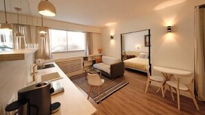 A modern hotel room with a kitchenette, a sofa, a bed, and a small dining table. - Elegant Apt near Eiffel Tower, Fast WiFi, (Paris)