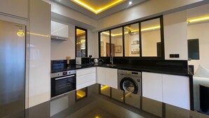 Een moderne keuken met een koelkast, oven, magnetron, spoelbak en wasmachine.