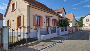 Ein zweistöckiges Haus mit roten Ziegeln auf dem Dach, einem verschlossenen Eingang und einem gepflasterten Auffahrtsweg.
