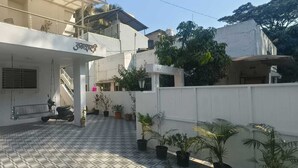 A residential building with a covered entrance, tiled flooring, and potted plants.