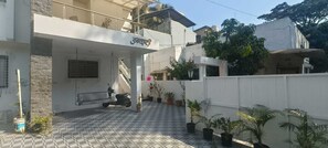 A residential building with a covered entrance, tiled flooring, and potted plants.
