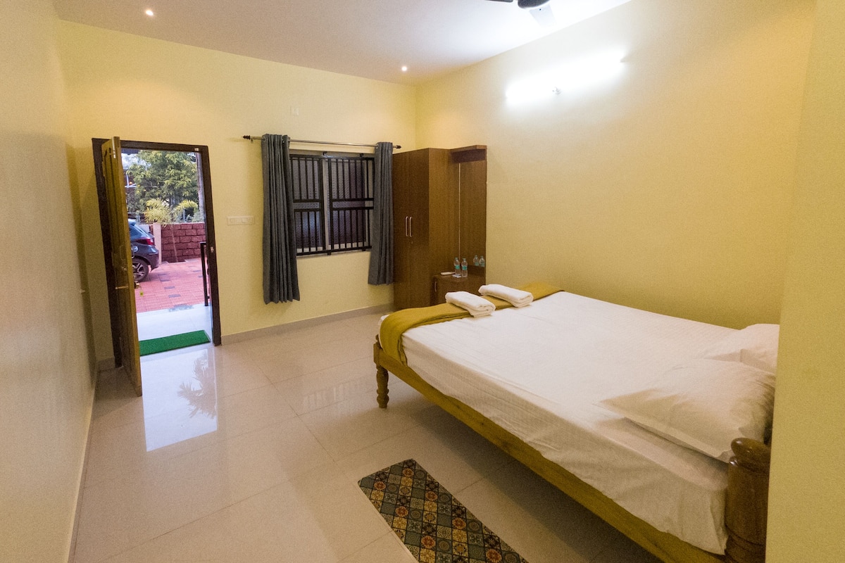 Una habitación de hotel con cama, armario, ventana con cortinas y puerta que da al exterior.