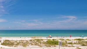A beach with a clear sky, sandy shore, and a few people and umbrellas. - AMI Bridgeport 202 -Beach View Retreat+Resort Pool (Bradenton Beach)