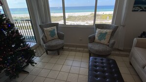 A room with two patterned armchairs, a bench, and a Christmas tree. - AMI Bridgeport 202 -Beach View Retreat+Resort Pool (Bradenton Beach)