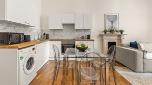 Una cocina moderna con armarios blancos, un salpicadero de mármol y lavadora incorporada.