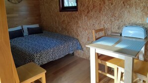 A cozy room with a bed, a small window, a clock, and a toaster on a table. - Acorn corner in a wooden house (Leiria)