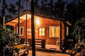 A wooden cabin with a porch, a bench, and a small table.