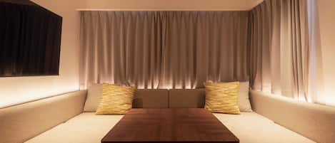 Una habitación moderna con una mesa de madera, un sofá beige y dos almohadas a rayas.