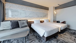 Et moderne hotelværelse med en stor seng, en sofa, et lille bord og en væg med marmorindslag.