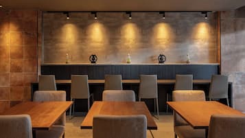 A modern dining area with a long wooden table and several upholstered chairs.