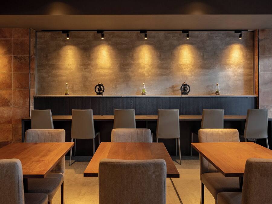 A modern dining area with a long wooden table and several upholstered chairs.