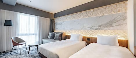 A hotel room with two beds, a sofa, a chair, and a large window with curtains.