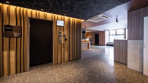 En moderne hotellobby med et marmortak, en reception og et gulv med et mønstret flisemønster.