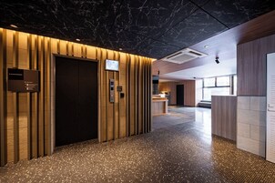 En modern hotellobby med ett tak av marmor, en receptionsdisk och ett golv med ett mönstrat kakel.