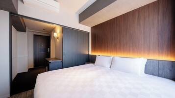 A modern hotel room with a large bed, a wooden headboard, a desk, and a mirror.