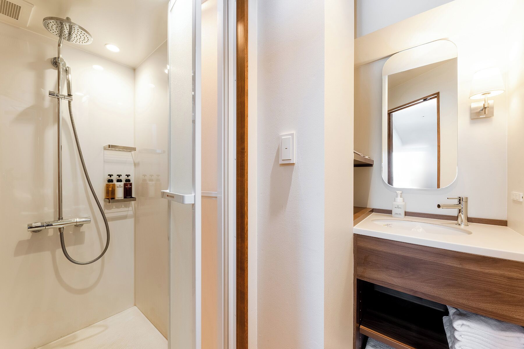 A modern bathroom with a glass shower enclosure, a vanity with a mirror, and a towel rack.