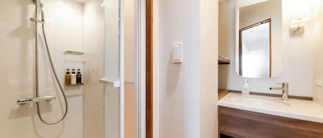 Un baño moderno con cabina de ducha de vidrio, tocador con espejo y perchero.