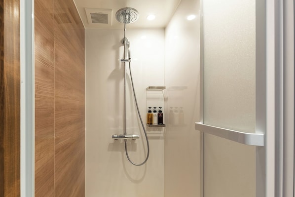 Une salle de bain moderne avec une douche, un mur en bois et une étagère contenant des articles de toilette.