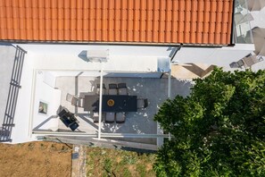 Eine Dachterrasse mit Tisch und Stühlen, einer kleinen Sitzecke und Blick auf einen Garten.