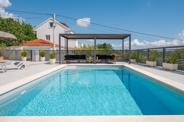 A swimming pool with a covered seating area and potted plants. - Family Holiday Home in Tugare With Pool (Omis)