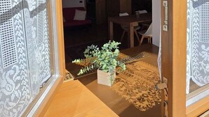 An open doorway leading to a room with a wooden ceiling, a small table with chairs, and a potted plant. - Maison Cavalese - Wild Forest - Tranquility at 2 steps from the center (Cavalese)