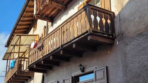 A two-story building with wooden balconies, a stone facade, and a cobblestone ground. - Maison Cavalese - Wild Forest - Tranquility at 2 steps from the center (Cavalese)