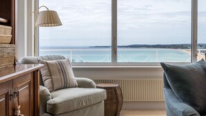 Une pièce avec vue sur la mer, un canapé, une lampe et une petite table ronde.