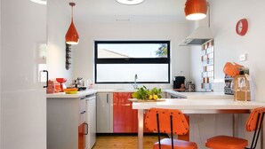 Een moderne keuken met een centraal eiland, twee hanglampen en een raam met uitzicht.