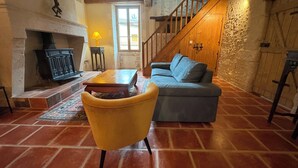 Una sala de estar acogedora con chimenea, un sofá, un sillón amarillo y una escalera.