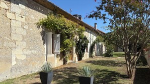 Un patio con muros de piedra, plantas en macetas y una zona con césped.