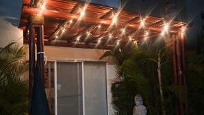 A covered outdoor area with a statue, a pergola with string lights, and a building in the background. - Acapulco's House with 3 gigant pools, massive gardens and 3 besrooms (Acapulco de Juárez)